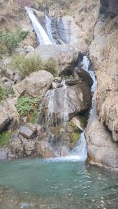 a waterfall on the side of a mountain with water at Eye love peace cafe in Manīkaran