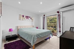 a white bedroom with a bed and a balcony at Baîeta - Appt climatisé Jacuzzi vue mer in Menton