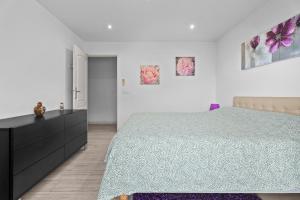 a white bedroom with a bed and a dresser at Baîeta - Appt climatisé Jacuzzi vue mer in Menton +7 photos