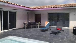 un patio con tavolo e sedie e una piscina di Villa Suarticcia, 6 pers, piscine chauffée, 3 min plage en voiture a Sainte-Lucie de Porto-Vecchio