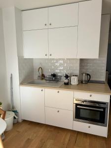 eine Küche mit weißen Schränken und einem Herd mit Backofen in der Unterkunft Appartement lumineux Mairie des Lilas in Les Lilas + 7 Fotos