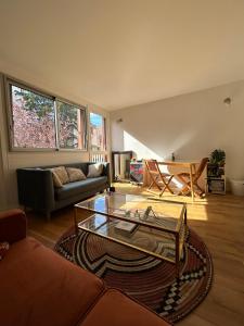 ein Wohnzimmer mit einer Couch und einem Glastisch in der Unterkunft Appartement lumineux Mairie des Lilas in Les Lilas