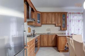 una cucina con mobili in legno e un frigorifero in acciaio inossidabile di Cosy 3BR home Apt with private balcony in B'Bugia a Birżebbuġa
