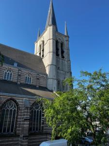 a church with a steeple on top of a building at Appartement ' Studio Stockholm' in Geel