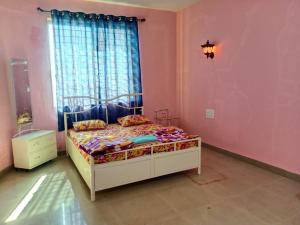 a bedroom with a bed in a pink room at Dev anand Villa in Mahabaleshwar