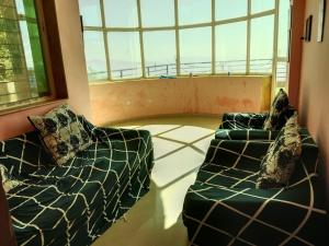 a living room with two couches and a large window at Dev anand Villa in Mahabaleshwar