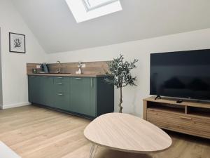 ein Wohnzimmer mit einem Tisch und einem großen Fernseher in der Unterkunft Le Carcos in Rocroi