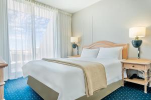a bedroom with a large white bed and a window at Dolphin Beach Hotel Self Catering Apartments in Bloubergstrand