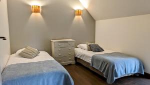 a bedroom with two beds and a dresser and lights at Magnifique longère, proche plages et Vannes centre in Séné