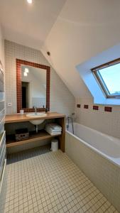 a bathroom with a sink and a tub and a mirror at Magnifique longère, proche plages et Vannes centre in Séné
