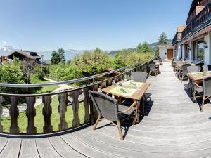 a wooden deck with tables and chairs on a balcony at Alpe Fleurie Residence in Villars-sur-Ollon