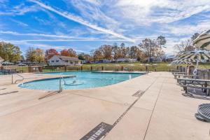 a swimming pool with chairs and an umbrella at Lakefront Retreat in Badin Shores Resort home in New London +34 photos