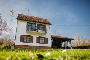 a small white house with a balcony in a field at Kuća za odmor Djedov šešir in Oriovčić