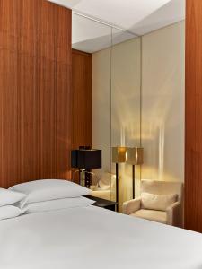 a bedroom with a bed and a chair and a mirror at Le Metropolitan, Paris Tour Eiffel, a Tribute Portfolio Hotel in Paris