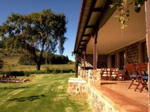 a porch of a house with chairs and a tree at Watersmeet cottages in Dullstroom +16 photos