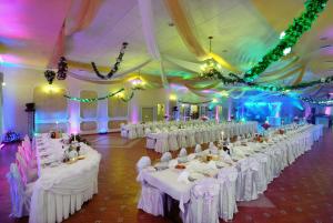 a banquet hall with white tables and white chairs at Podgrodzie in Kowal