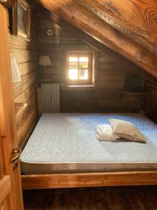 a bed in a wooden cabin with a window at Villa millefiori falda argentera in Sauze di Cesana