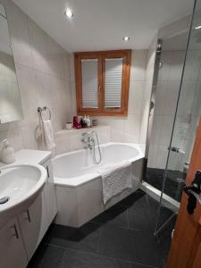 a bathroom with a tub and a sink and a shower at Lovely 3 bedroom apartment in Schönried