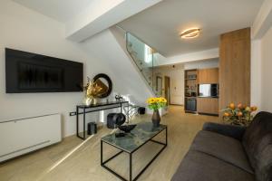 a living room with a couch and a tv on a wall at Platinum Suites in Ioannina