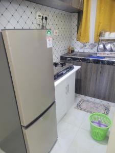 a kitchen with a refrigerator and a basket on the floor at Crystaljen Apartment in Mtwapa