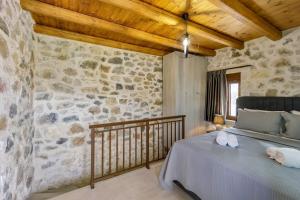 a bedroom with a bed and a stone wall at Villa Errika Koxari by Estia in Kóxari +71 photos