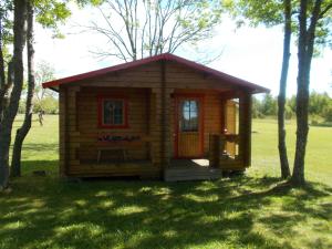 a small log cabin in a field with trees at Ula-Hansu talu in Suur-Rootsi