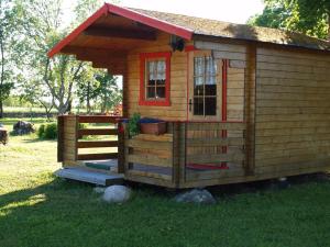 a small wooden cabin with a porch and a window at Ula-Hansu talu in Suur-Rootsi +9 photos