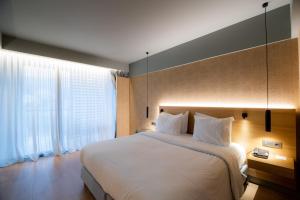 a bedroom with a large bed and a large window at Magnes Hotel in Volos