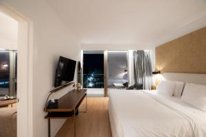 a hotel room with a bed and a desk with a television at Magnes Hotel in Volos