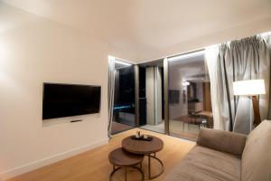 a living room with a couch and a tv and a table at Magnes Hotel in Volos