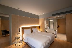 a bedroom with a large white bed and a desk at Magnes Hotel in Volos