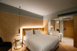 a bedroom with a large white bed and a table at Magnes Hotel in Volos