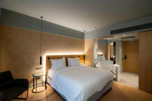 a bedroom with a large white bed and a chair at Magnes Hotel in Volos