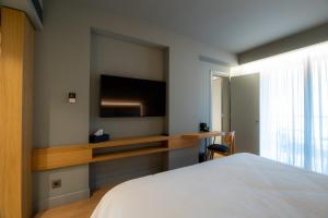 a bedroom with a bed and a tv on the wall at Magnes Hotel in Volos