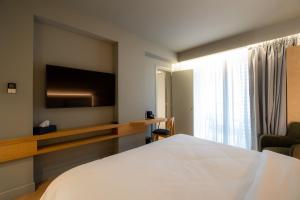 a hotel room with a bed and a flat screen tv at Magnes Hotel in Volos