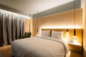 a bedroom with a large white bed and a chair at Magnes Hotel in Volos