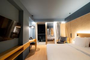 a hotel room with a bed and a desk and a tv at Magnes Hotel in Volos