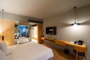 a bedroom with a bed and a desk and a tv at Magnes Hotel in Volos