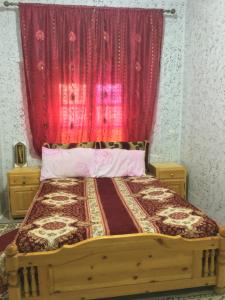 a bedroom with a wooden bed with a red curtain at Ounilla valley in Tizgui nʼBarda