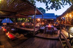 ein Restaurant mit Tischen und Stühlen auf einer Holzterrasse in der Unterkunft Castaway Resort Koh Lipe in Ko Lipe