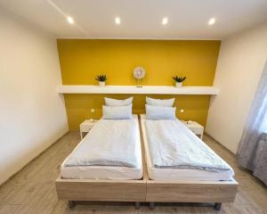 two beds in a room with a yellow wall at Ferienwohnung im Grießetal in Aerzen