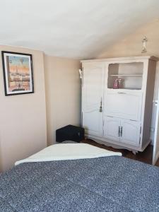 a bedroom with a bed and a white cabinet at Charmante maisonnette de caractère in Châteauroux