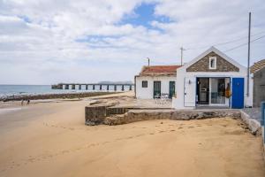 a house on the beach with a pier in the background at Casa Neverland in Vila Baleira