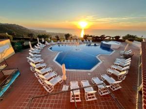 a group of chairs and a pool with the sunset at Marasusa Dreams in Parghelia