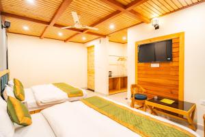 a room with two beds and a flat screen tv at Winterfell Stays Mussoorie in Mussoorie