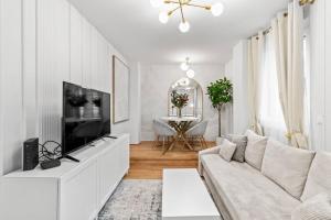 a white living room with a couch and a tv at Balkon I Parkplatz I 5 Minuten zum Einkaufszentrum I schnelles WLAN in Vienna