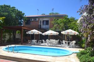 a swimming pool with chairs and umbrellas and a house at Hotel Nelly in São Gabriel
