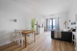 a white living room with a table and a couch at Ribeira DIlhas Beach Apartment in Ericeira