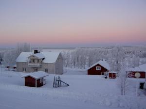 a house and a barn with snow on the ground at Lomamaja Pekonen Apartments in Muonio