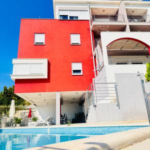 a red building with a swimming pool in front of it at Luxury Apartments Villa Lenka in Podstrana